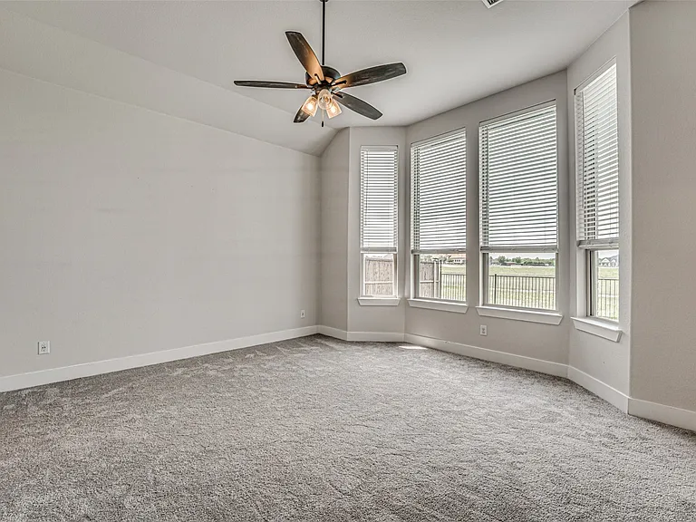 Spacious room with a vaulted ceiling, ceiling fan, and carpeted flooring