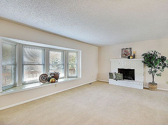 Wood-burning fireplace with brick surround in liv rm along w/ large bay window