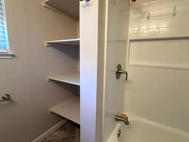 Bathroom includes a tub/shower combo with built-in storage for towels and linens.