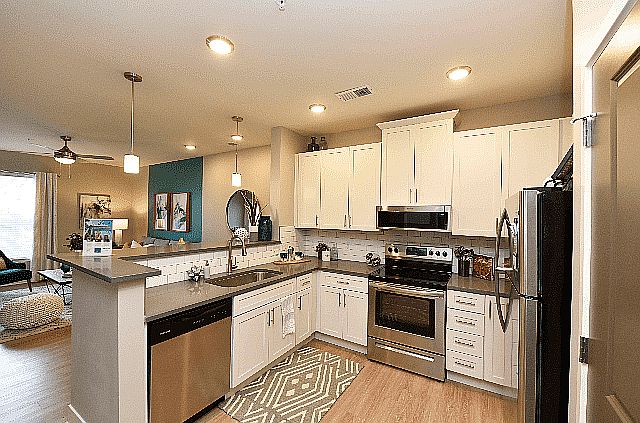 White cabinetry, stainless steel appliances, and pendant lighting meet in this open-concept kitchen that flows seamlessly into your living space.