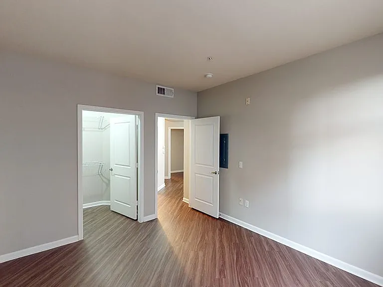 Spacious apartment bedroom with large closet and wood-style flooring.