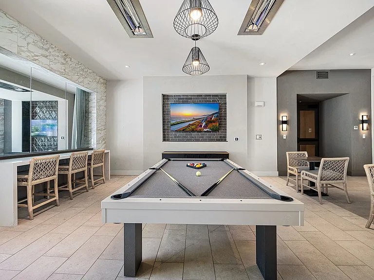 Game lounge with billiards table, bar seating, and mounted TVs