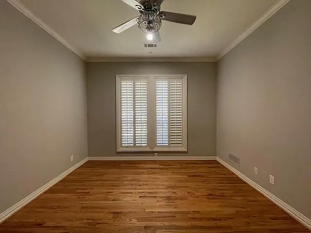 Spare room with wood finished floors, crown molding, and ceiling fan