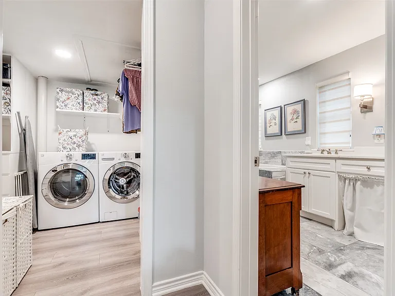 Dedicated laundry room featuring light wood-finish flooring, built-in shelving, and two front-loading appliances