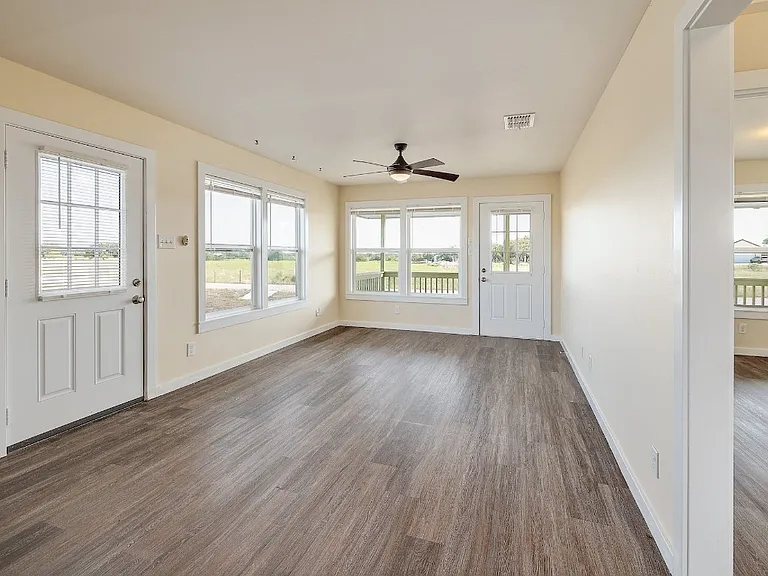 Standing in the kitchen looking into the living space. You can see into one bedroom on the right, with the side exit on the left.