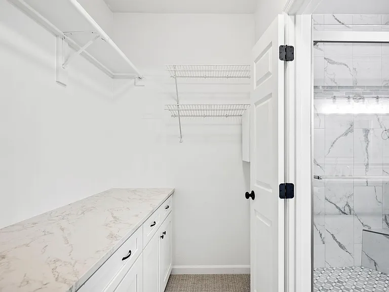 Main bedroom walk in closet with cabinets, drawer and counter top. Freshly painted, new carpet and new clothes hanging rod.