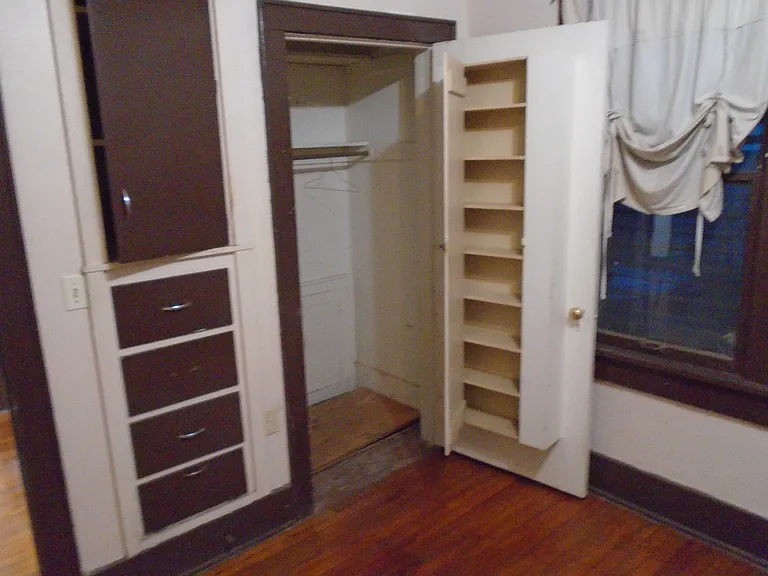 View of the North east corner of bedroom , showing the closet with open door on the right side and the storage drawers and cabinet on the left.
