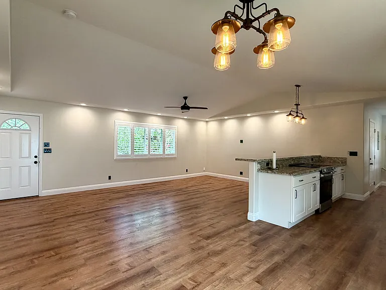 Open concept living area with front entrance, living, dining, & kitchen areas