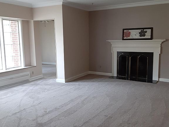 living room with wood burning fireplace, large bay window with marble window seat, new carpet, leading to large den
