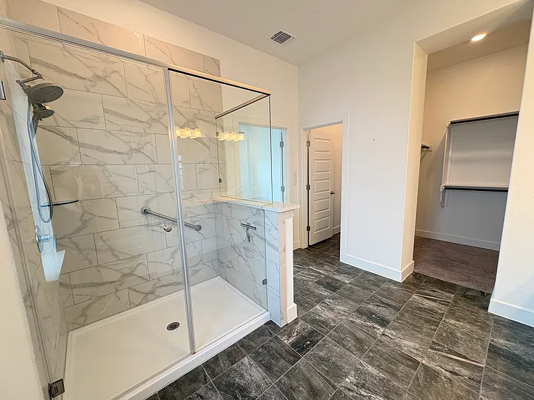 Primary bath with walk in shower, double vanity, huge shared walk in closet, linen closet with floor to ceiling shelving and toilet closet.
