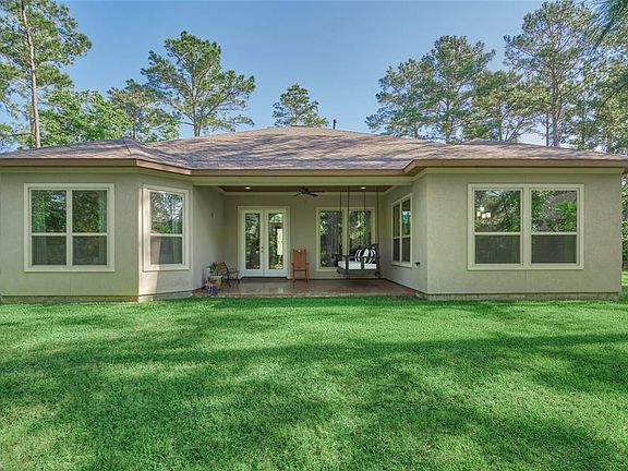 Spacious backyard and peaceful covered porch with stained flooring.
