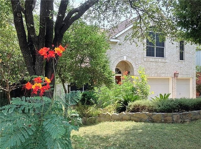 Welcome home! This view of the front of the home was taken when the flowers were in bloom. The landscaping was done with drought and deer resistant plants including a front yard of heat-tolerant hybrid Zoysia grass!