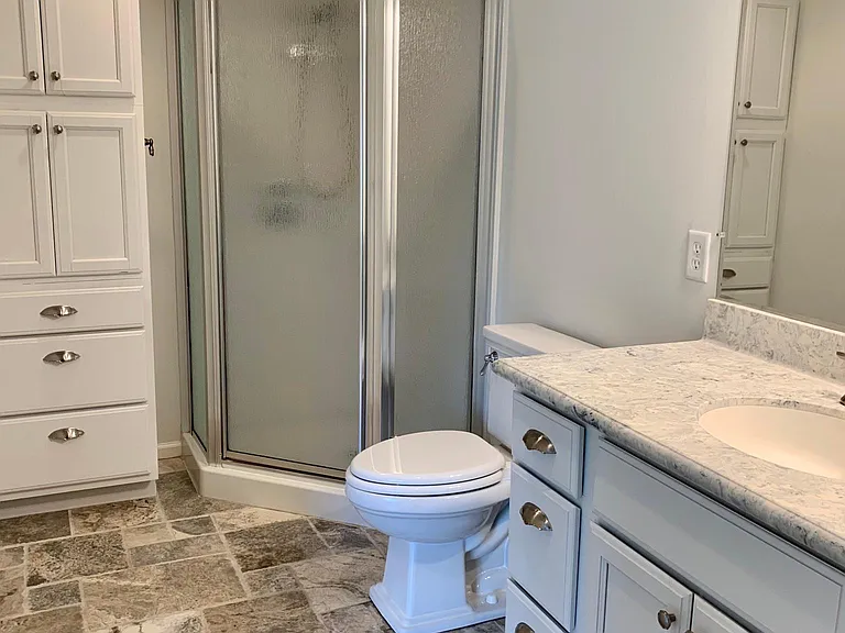 Updated en-suite. Curated stone flooring and marble counter. One of the Maters two walk in closets is accessed off of this room.