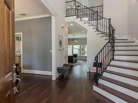 Wood flooring and cascading stairs welcome you into the home.