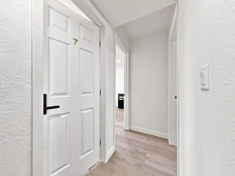 Clean interior hallway with updated flooring and multiple doorways for easy access to bedrooms and shared areas.