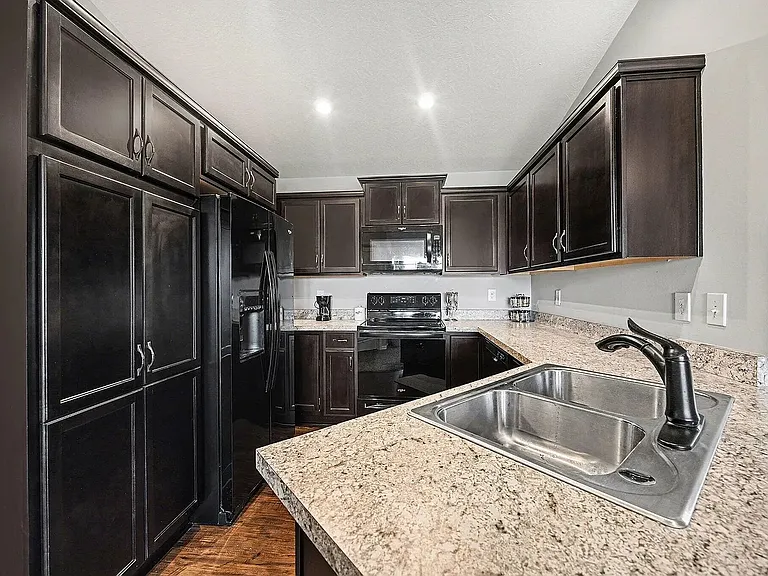 Fully equipped kitchen featuring ample cabinet space, generous countertops, black appliances, and a breakfast bar_perfect for cooking, dining, and entertaining in a comfortable open-concept setting.