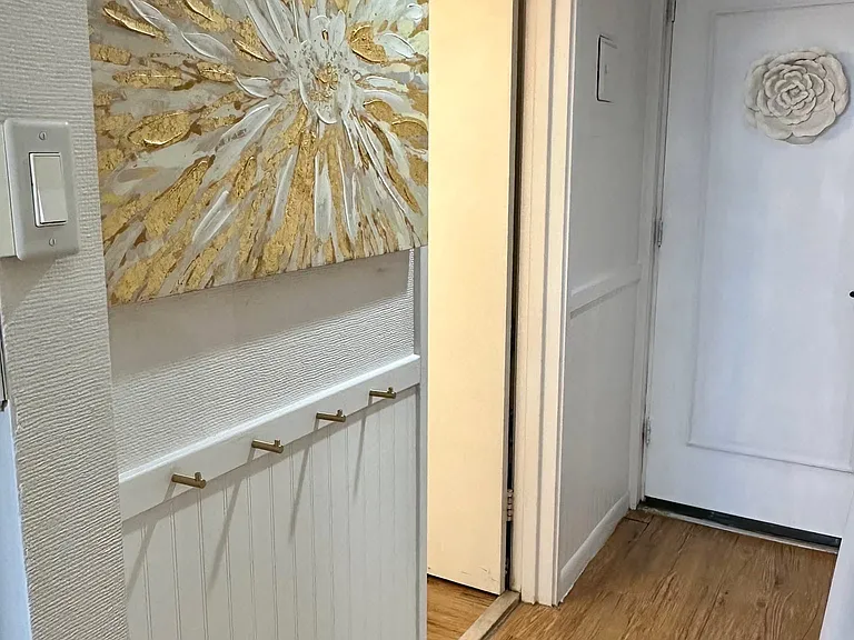 Hallway with closet, beadboard ,and gold hooks for coats and bags