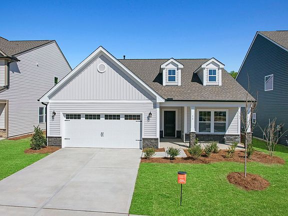 A white house with a gray roof and a white garage door is sitting on top of a lush green lawn.