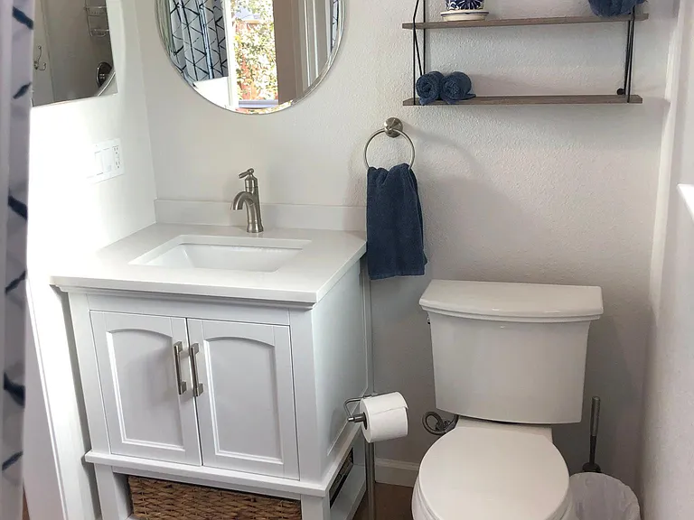 Bathroom has ample storage with a medicine cabinet, vanity cabinet, and shelves. Towels are included in furnishings.