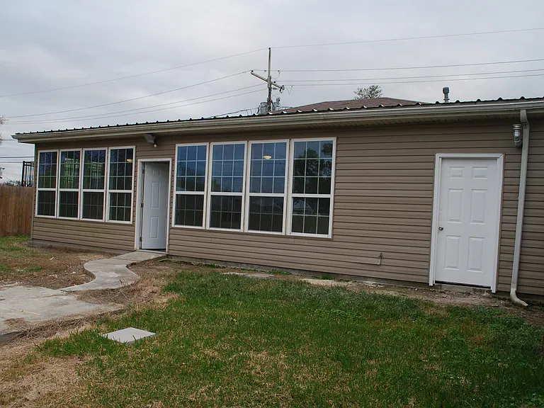 Back yard, will green up with weather and a bit of mowing and attention. Water heater/storage access door on right.