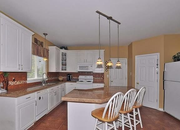 Large kitchen with butterfly island and breakfast bar, ceramic tile flooring, 42 inch cabinets accen