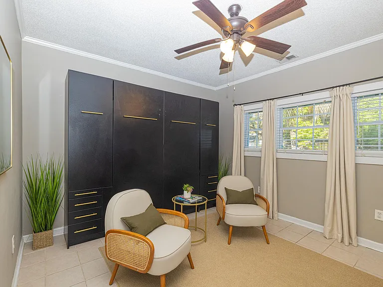 Bedroom with two lounge chairs, queen size Murphy bed, and Smart TV