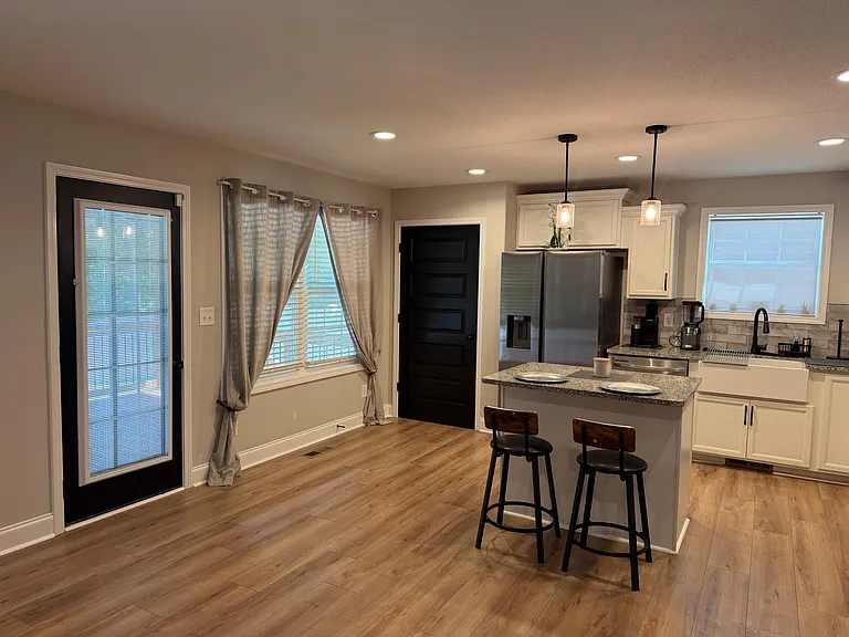 Kitchen features granite-look counters, stainless steel fridge, and a breakfast bar with seating plus easy backyard access.