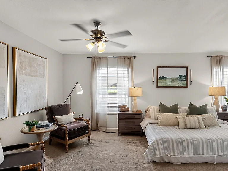 Inviting bedroom with elegant decor, featuring a cozy bed, stylish armchairs, and warm ambient lighting.