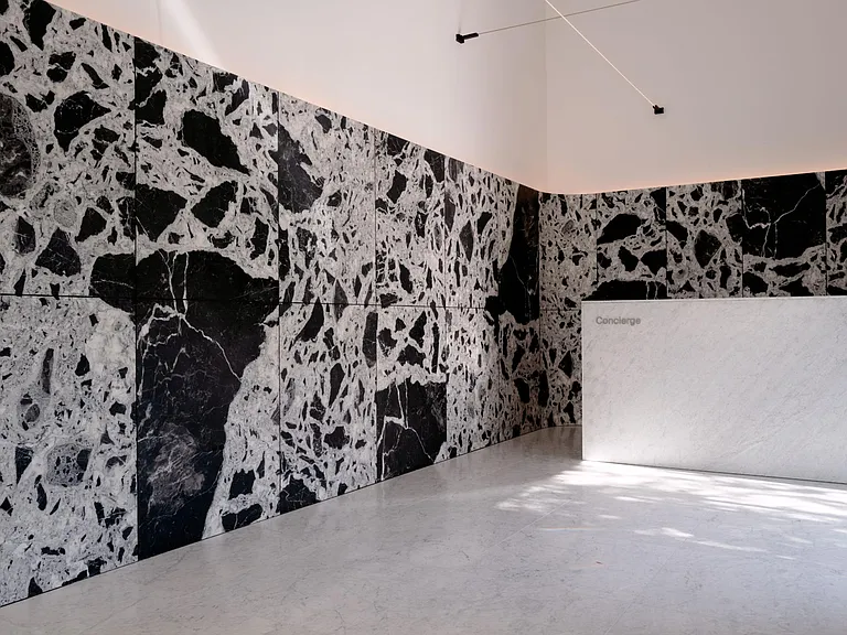Striking Concierge Lobby with Grand Antique Marble Accents _ The concierge lobby makes a bold statement with expansive sculptural Grand Antique marble walls, soaring ceilings, and refined architectural lighting.
