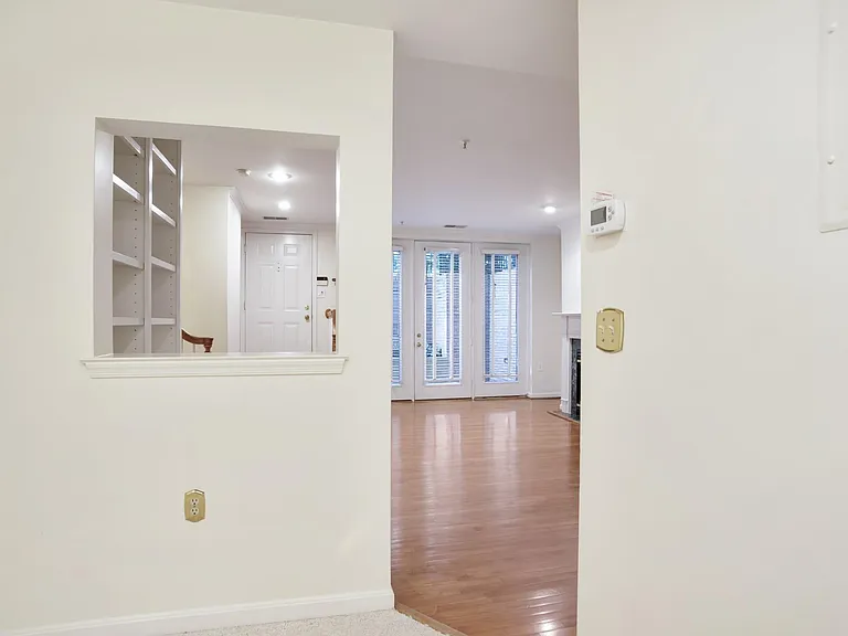 View of living space and front door from the den. Double doors open onto patio.