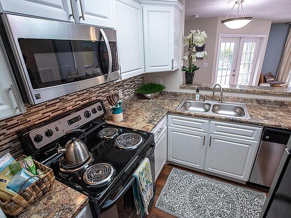 Updated kitchens featuring granite-style counter tops, white cabinetry, and wood-style flooring.