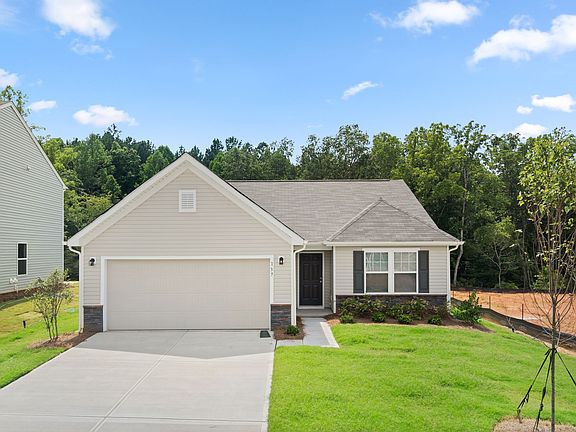 A house with a large garage and a lush green lawn in front of it.