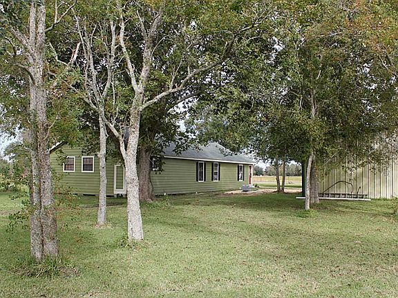 View of the house from the back left of the property featuring mature trees.