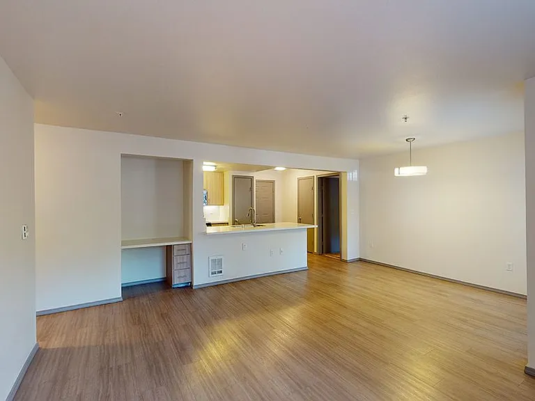 Apartment kitchen with stainless steel appliances, quartz countertops and wood-style flooring.