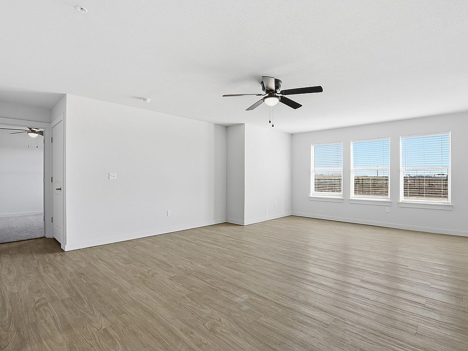 Bright and spacious living room with sleek wood flooring, large windows offering natural light, and a modern ceiling fan.