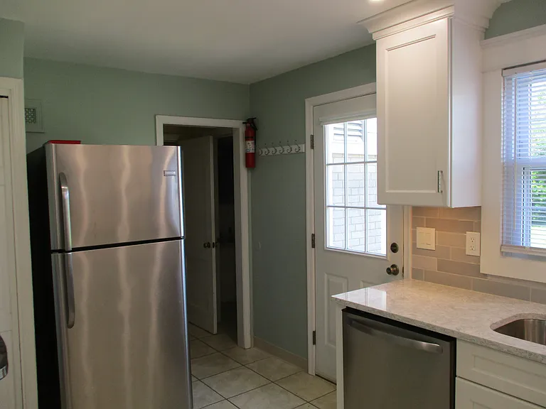 View of kitchen looking towards 1st floor powder room and lower level access. Kitchen also has a pantry.