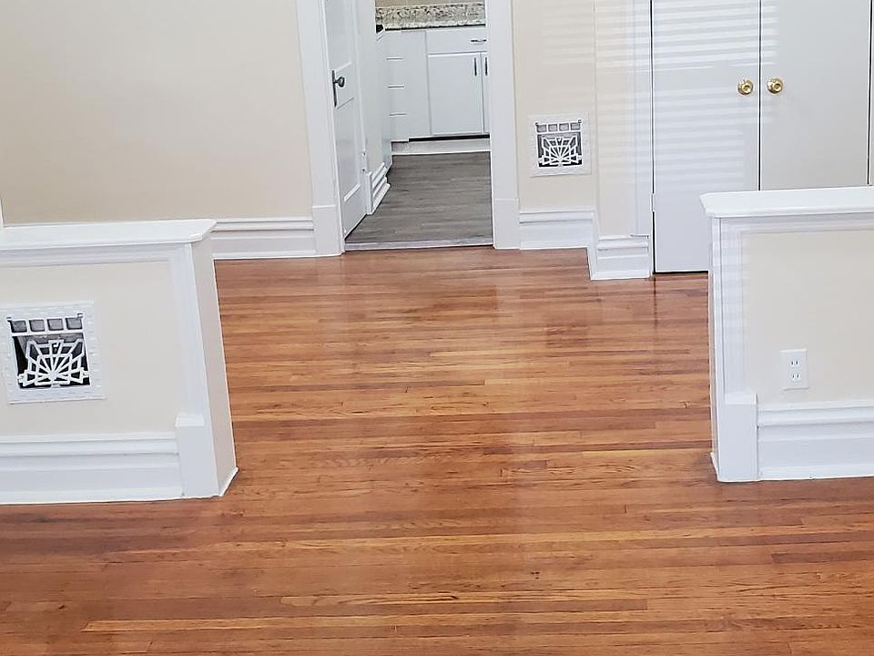 A view from the front looking into the front two rooms with hardwood floors and connecting archway.
