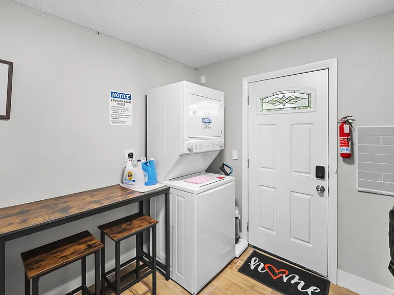 Convenient laundry area with stacked washer/dryer, folding counter, and nearby entry for easy everyday routines.