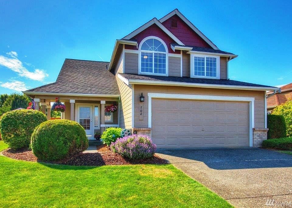 Front of home showing off new roof, fresh paint, mature landscaping and covered entrance on the left
