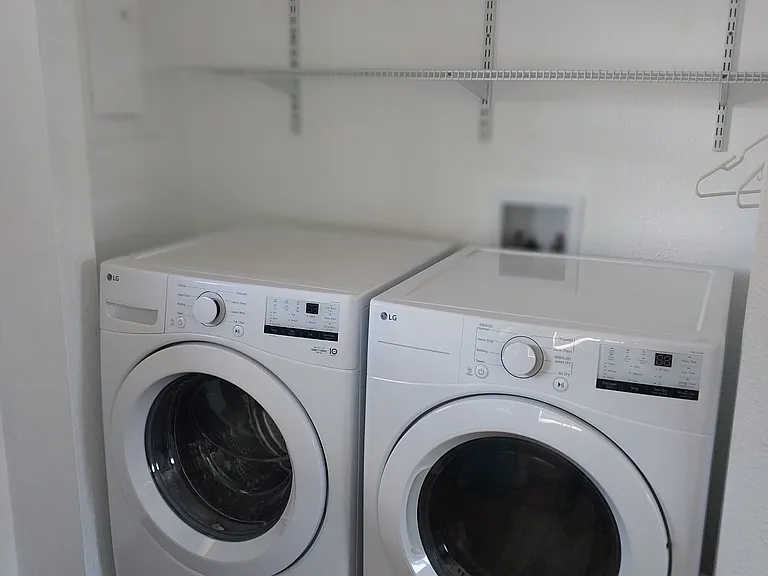 Brand new LG washer and dryer with storage shelving in laundry room