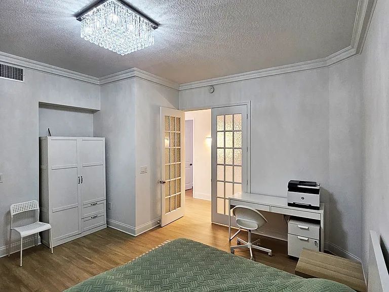 An office-bedroom with a desk and a printer.