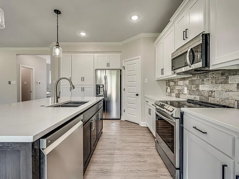 Stone backsplash with white Shaker cabinets and dark hardware gives this home a contemporary flair.