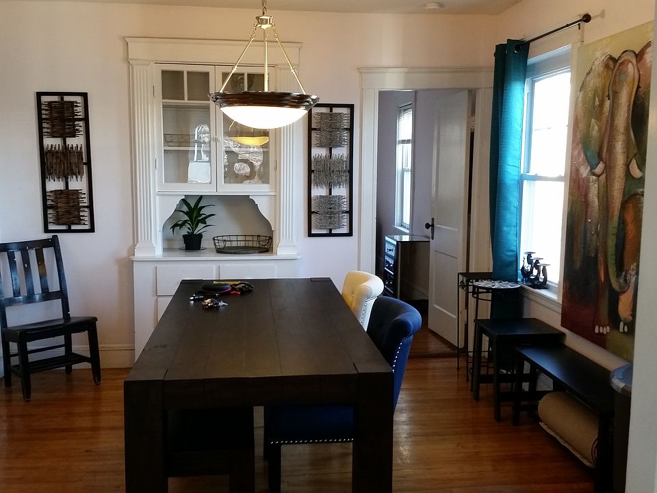 Spacious dining room featuring large windows to fill the room with daylight, exquisite original built-in China cabinet, gleaming hardwood floors, and pendant light!
