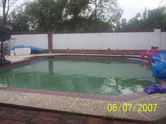 Large inground pool with large cool deck surrounding w/ block planter 