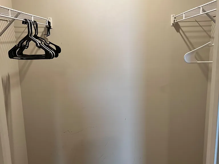 Walk-in closet with dual wire shelving and hanging rods for easy organization of clothing and accessories.
