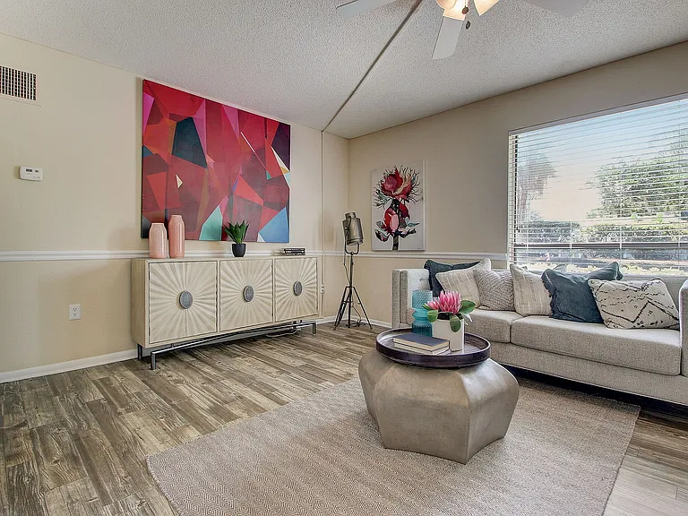 Modern living room with stylish decor, vibrant abstract wall art, and a cozy gray sofa accented by colorful cushions.