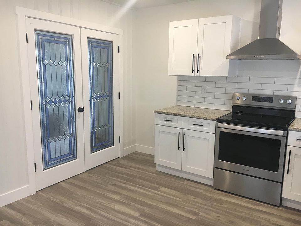 Kitchen with electric range and hood. Stained glass doors lead to common room that can be used as dining room or TV room. Current tenant has a dining table in the kitchen in the area to the left of the stained glass door.