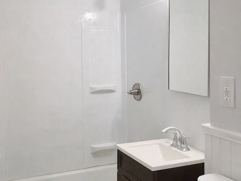 Downstairs full bathroom - new shower surround, recessed medicine cabinet, light fixture, fan, wainscoting, floor tile, Kohler toilet, fresh paint.