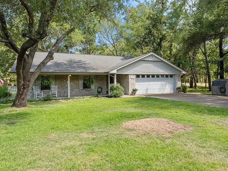 Ranch-style residence featuring a brick facade, covered front porch, and an attached two-car garage with a white panel door
