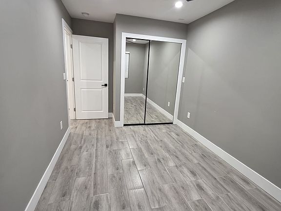 Modern bedroom, mirrored glass closet doors, ceiling fan.